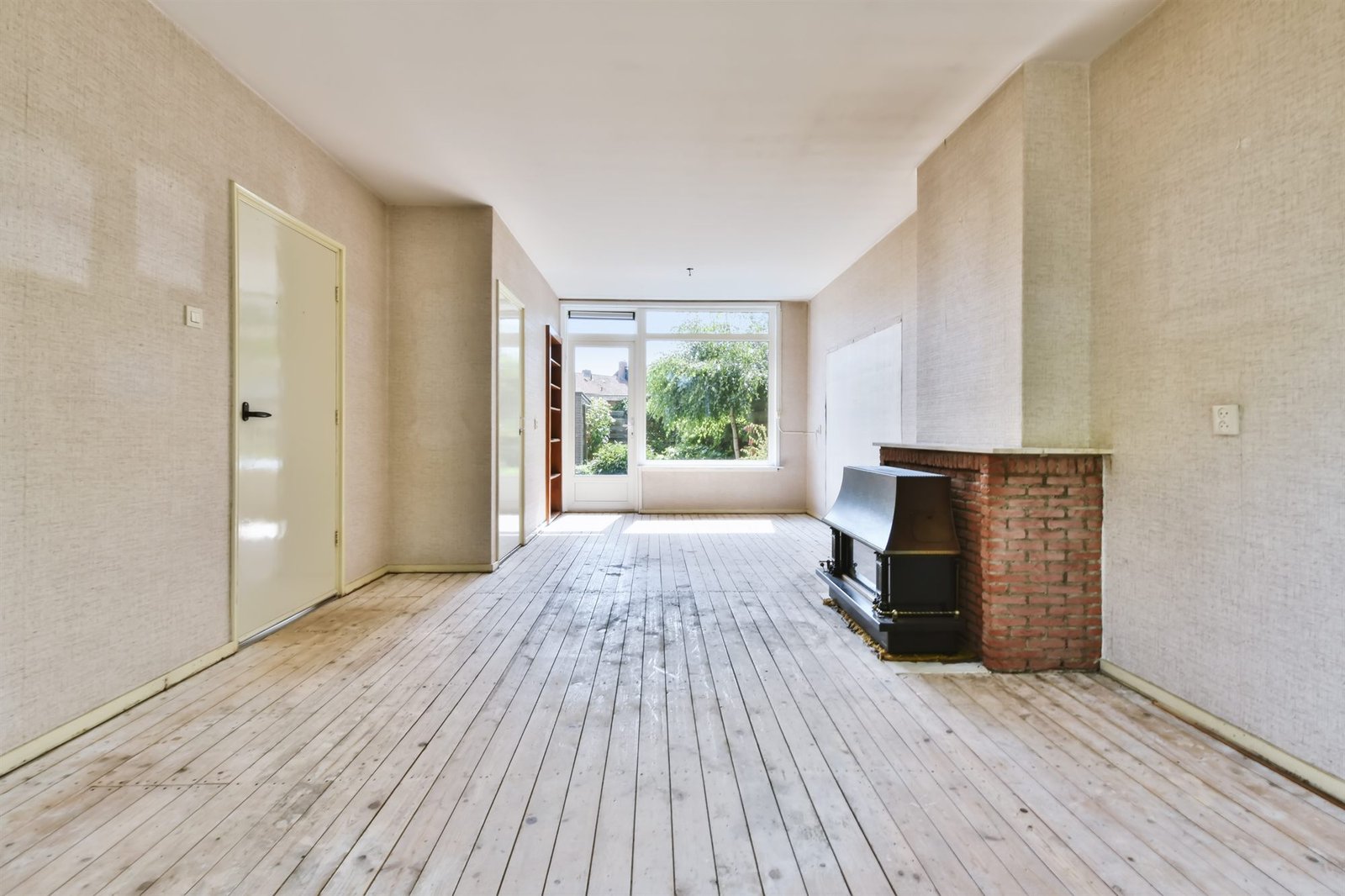 Lege woonkamer met houten vloer en open haard, klaar voor de oplevering
