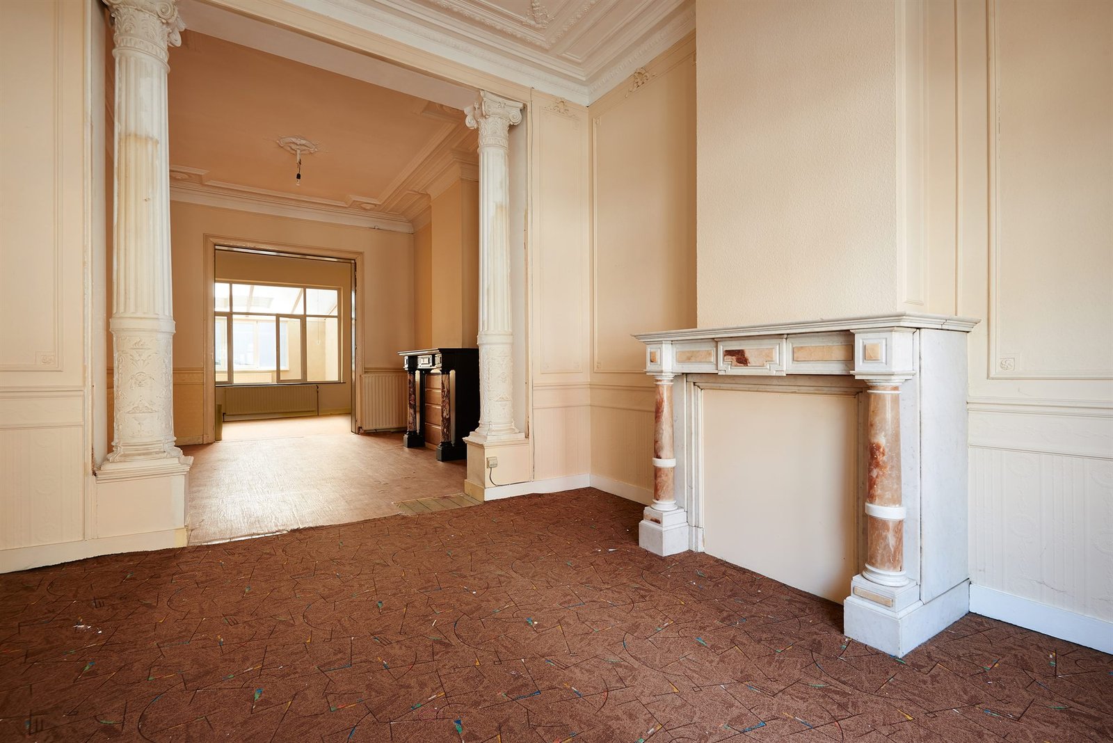 Leeggemaakte kamer in een herenhuis met marmeren schouw